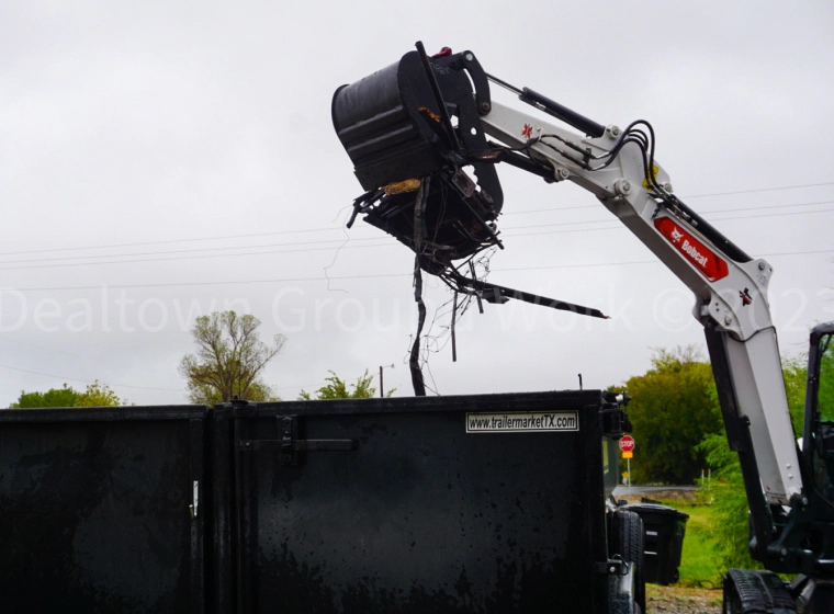excavator dumping debris into dumpster